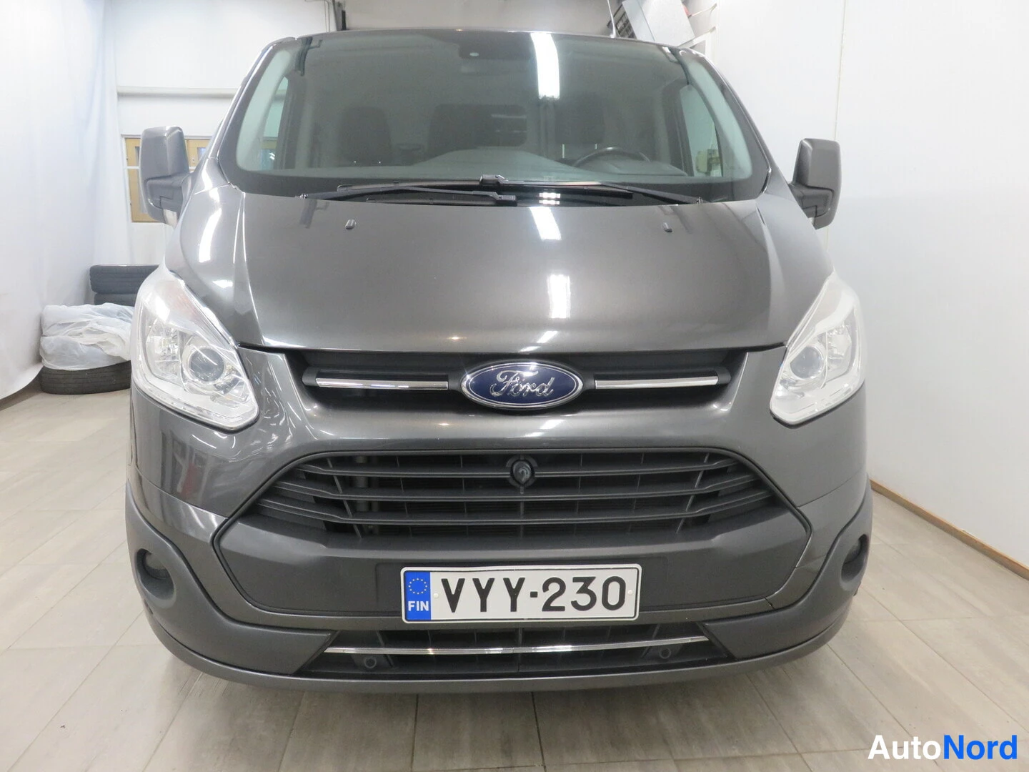 Edestä: Ford Transit Customin suora etunäkymä, etupuskerrassa suomalainen rekisterikilpi ja konepellillä Ford-merkki.