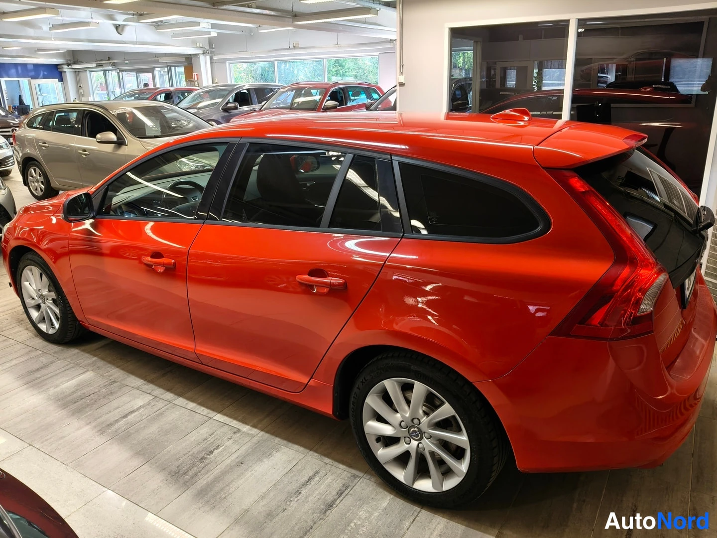 Takaviisto: Punaisen Volvo V60 -farmarin takakulma oikealta, takavalo ja perä näkyvissä auton katselussaautossa.