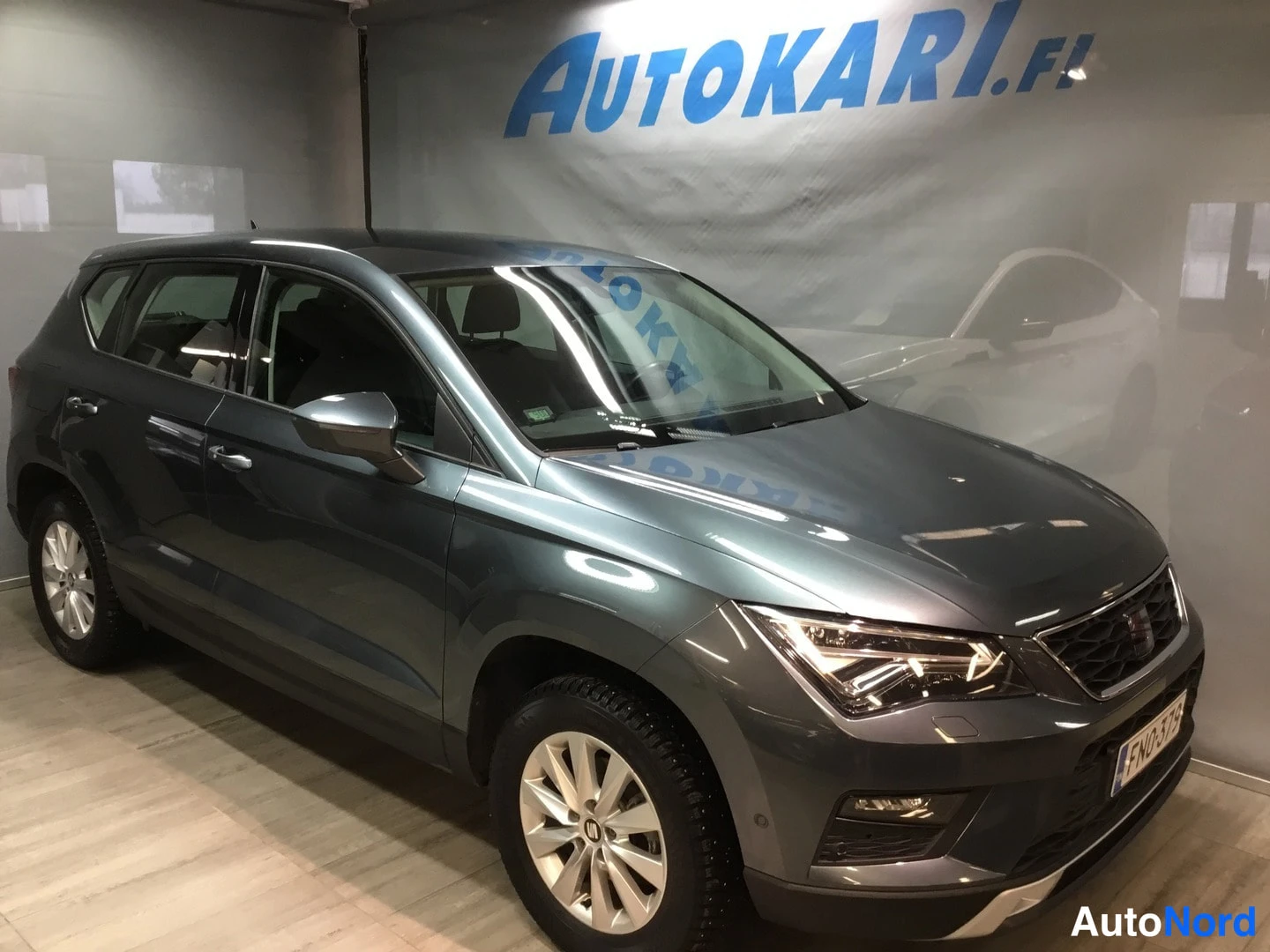 Etuviisto, nokka oikealle: Tummanharmaa SEAT Ateca -maasturi kuvattu kolmivartaloasennossa keulan oikealta puolella sisätiloissa, rekisterikilpi FN0-379.