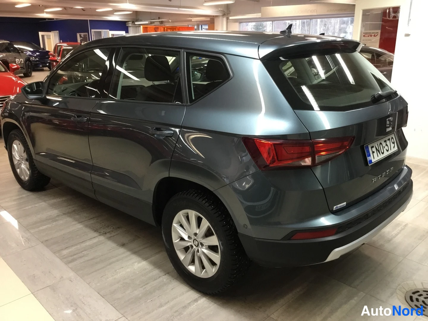 Takaviisto: Tummanharmaa SEAT Ateca takaviistosta vasemmalta nähtynä autosalissa, rekisterikilpi FN0-379.