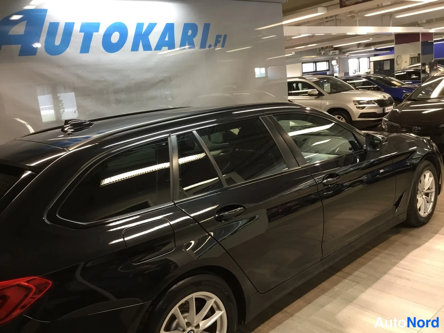 Takaviisto: Mustan BMW 5 Touring -farmaarin takakolmannnes vasemmalta: takavalot ja kylki näkyvät sisätiloissa.