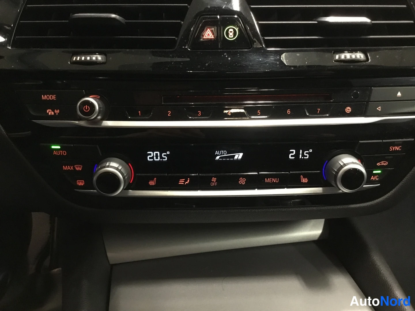 Edestä: Auton kojelaudan keskusta lähikuvassa: kaksivyöhykeilmastointi näytöillä 20.5° ja 21.5°, AUTO-tila ja A/C-painike näkyvät.