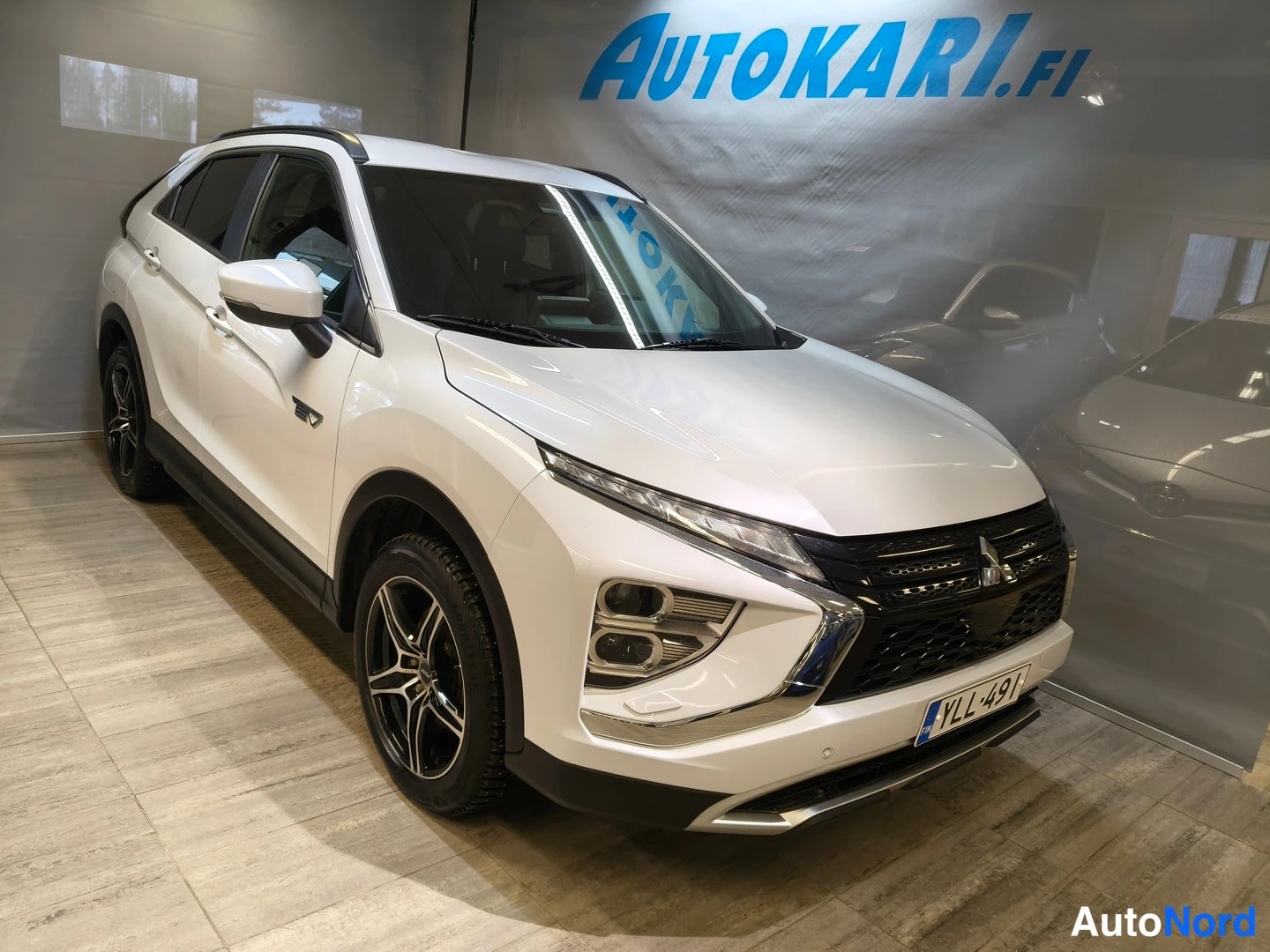 Etuviisto, nokka oikealle: Mitsubishi Eclipse Cross, valkoinen, etukulmakuva oikealta; etusäleikkö, ajovalot ja oikeanpuoleiset ovet näkyvissä, rekisterikilpi.
