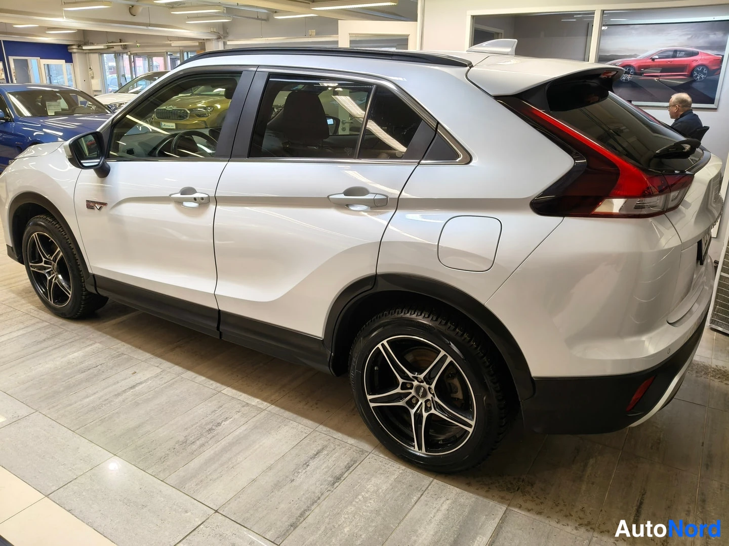 Takaviisto: Mitsubishi Eclipse Cross, valkoinen, takakulmakuva vasemmalta; takavalot, sivuovet ja takapyörä näkyvissä, mustat kevytmetallivanteet.