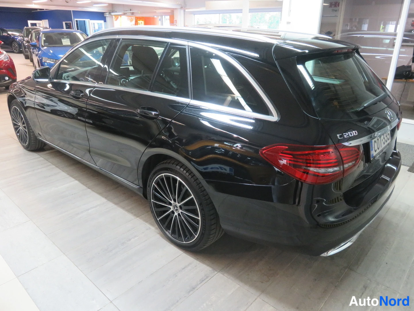 Takaviisto: Mercedes-Benz C 200 -farmarin takakulma mustana, takavalot ja rekisterikilpi näkyvissä sisätiloissa.