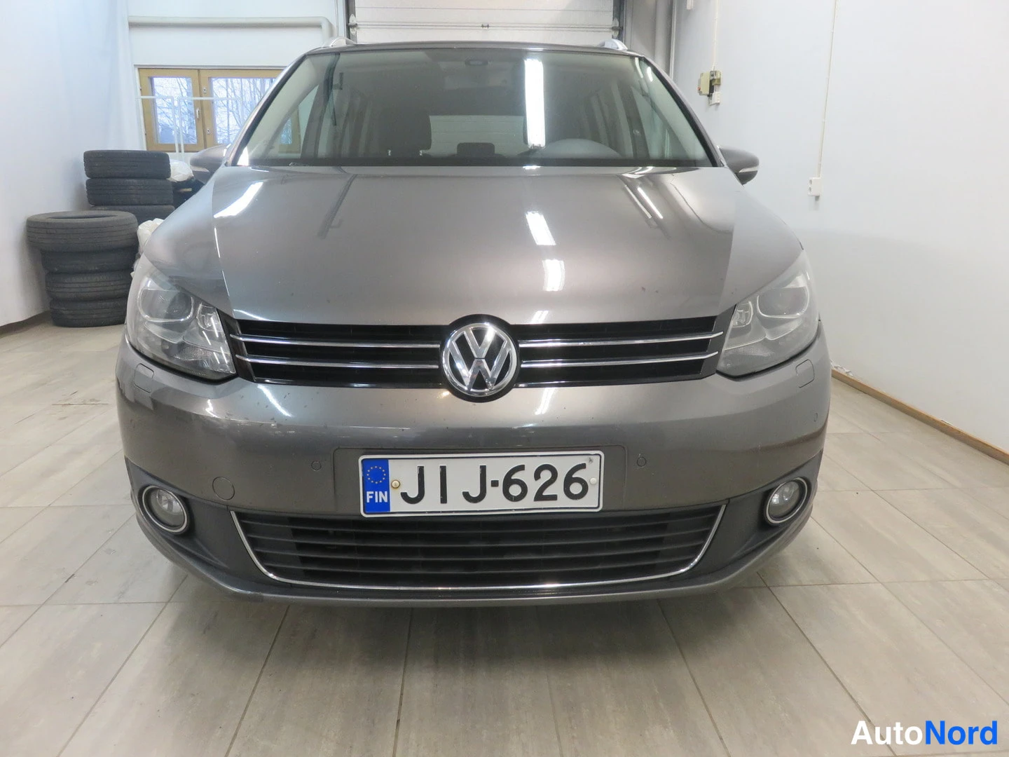 Edestä: Edestä päin kuvattu harmaan Volkswagenin keula, rekisterikilpi.