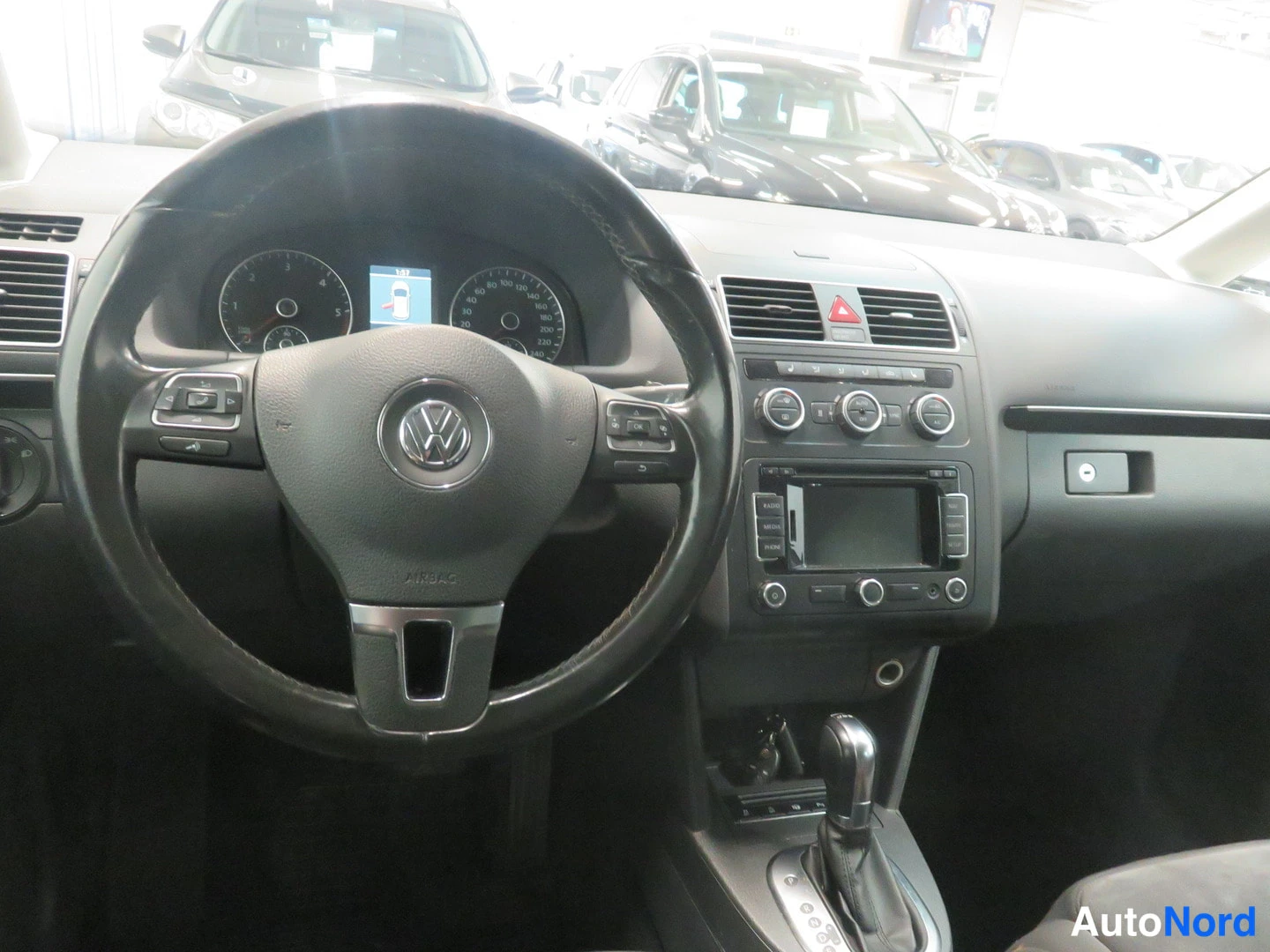 Muu: Ohjaamo Volkswagen-folkwith: musta ohjauspyörä VW-tunnuksella, mittaristo, radiopaneeli ja automaattivaihteen valitsin.