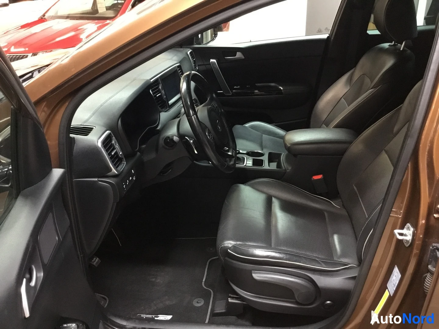 Etuistuimet: Interior cabin view from open driver's door, two front seats in black perforated leather with electric seat adjustment controls visible.