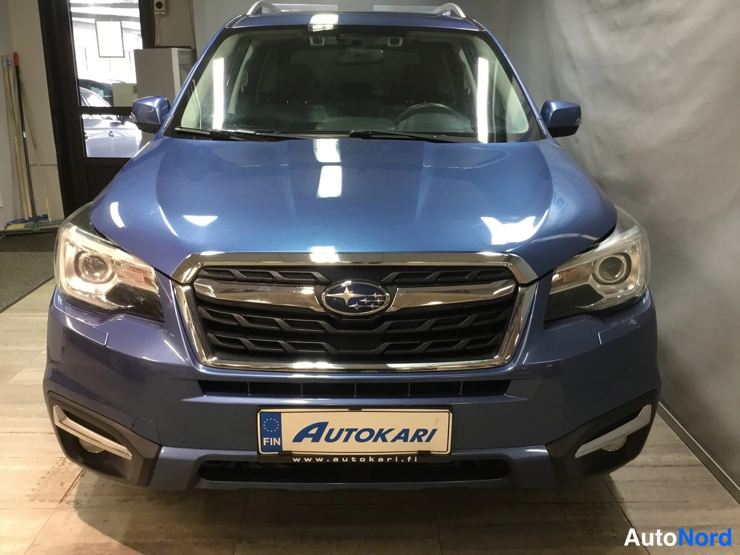 Edestä: Sininen Subaru Forester suoraan edestä, kattokaiteet ja sumuvalot näkyvät sisätiloissa