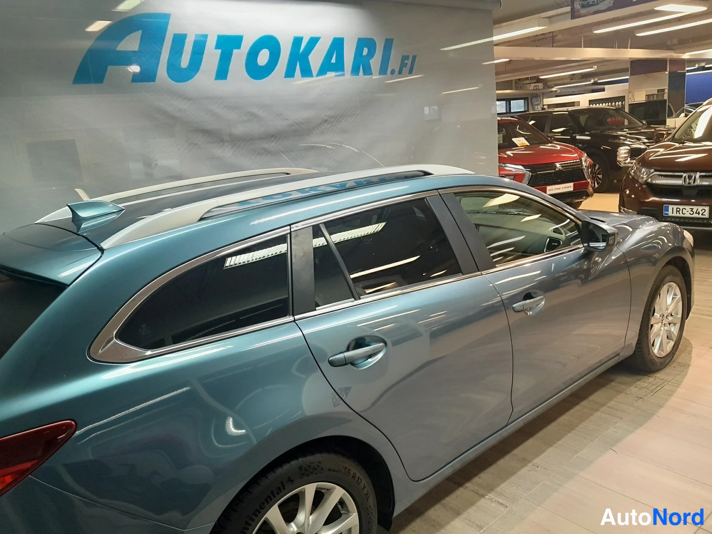 Takaviisto: Sinertävänharmaa Mazda 6 -farmari autonmyymälässä takakulmasta