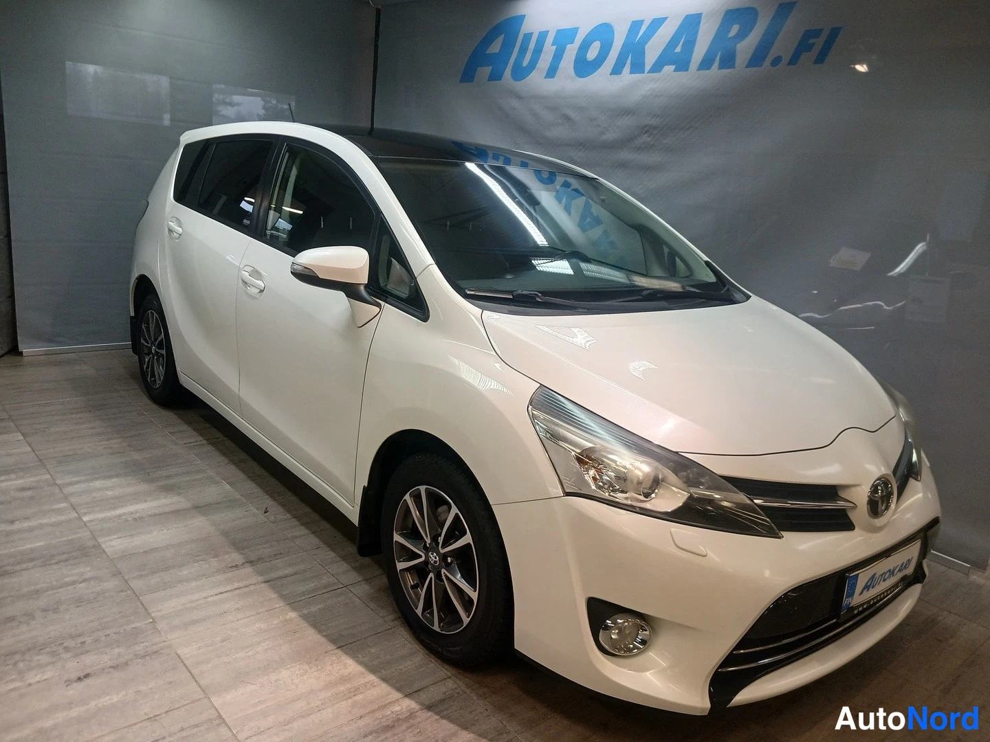 Etuviisto, nokka oikealle: Etukolmivartalokuva auton nokka oikealla; valkoinen autokori, kylkilokaleet ja harmaa betonilattiä.