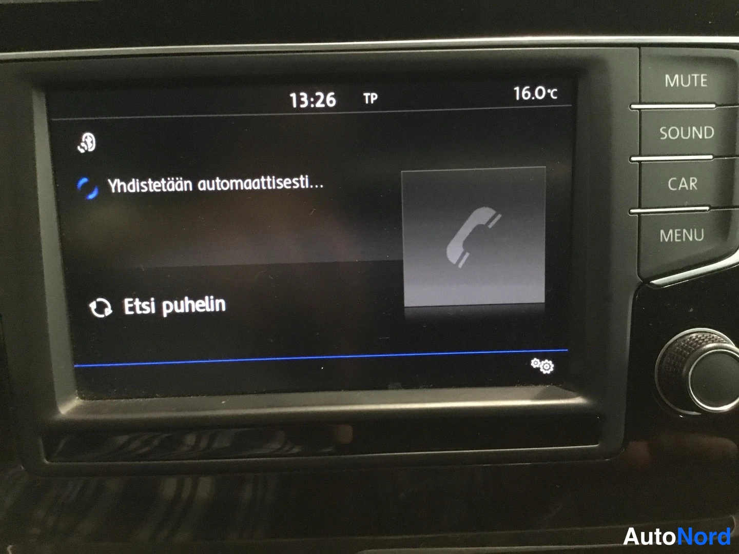Yksityiskohta: Auton kojelaudan infotainment-näyttö näyttää puhelimen yhdistämistä ja painikkeet MUTE, SOUND, CAR ja MENU.