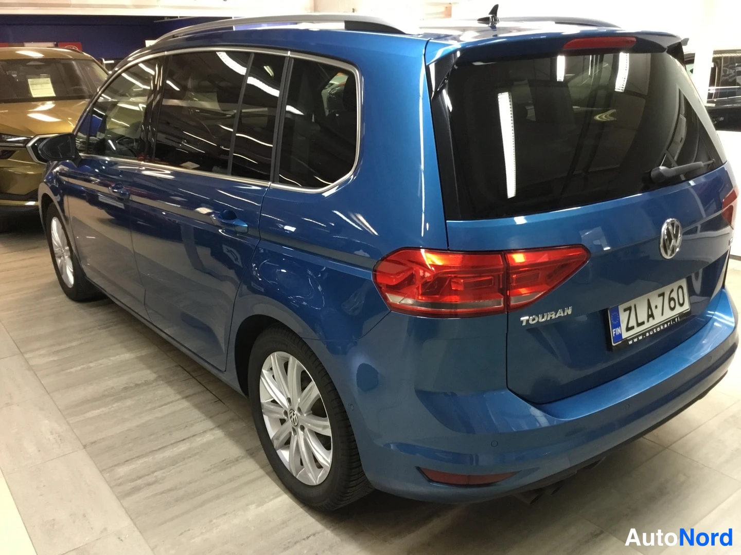Takaviisto: Sinisen Volkswagen Touranin takaosa ja oikea kylki takakulmasta, Touran-teksti ja rekisterikilpi takaluukussa.
