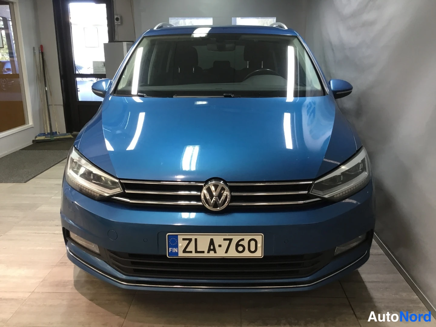Edestä: Sinisen Volkswagen Touranin etunäköyhta, rekisteritunnus.