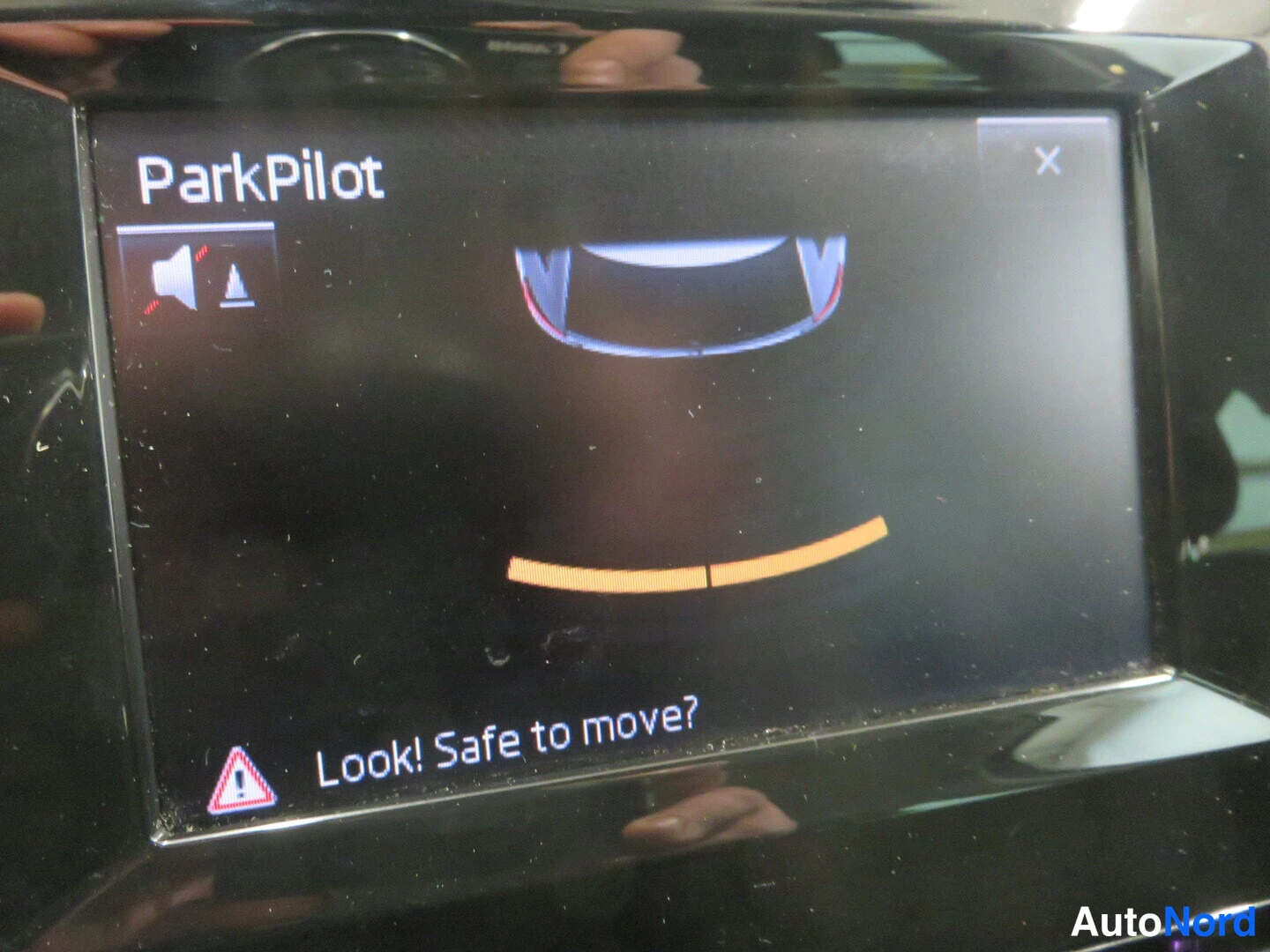 Muu: Infonäytön ParkPilot-kuva: auton ympärillä tuntikaaviot ja alareunassa teksti 'Look! Safe to move?'.
