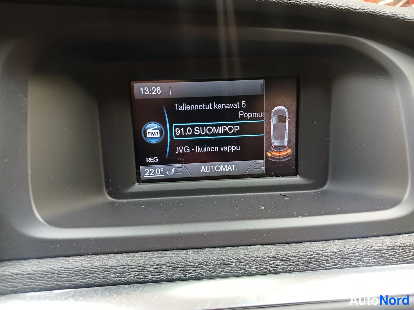 Muu: Kojelaudan infotainment-näyttö: radio FM1 91.0 SUOMIPOP, kello 13:26, lämpötila 22,0° ja teksti AUTOMAT.
