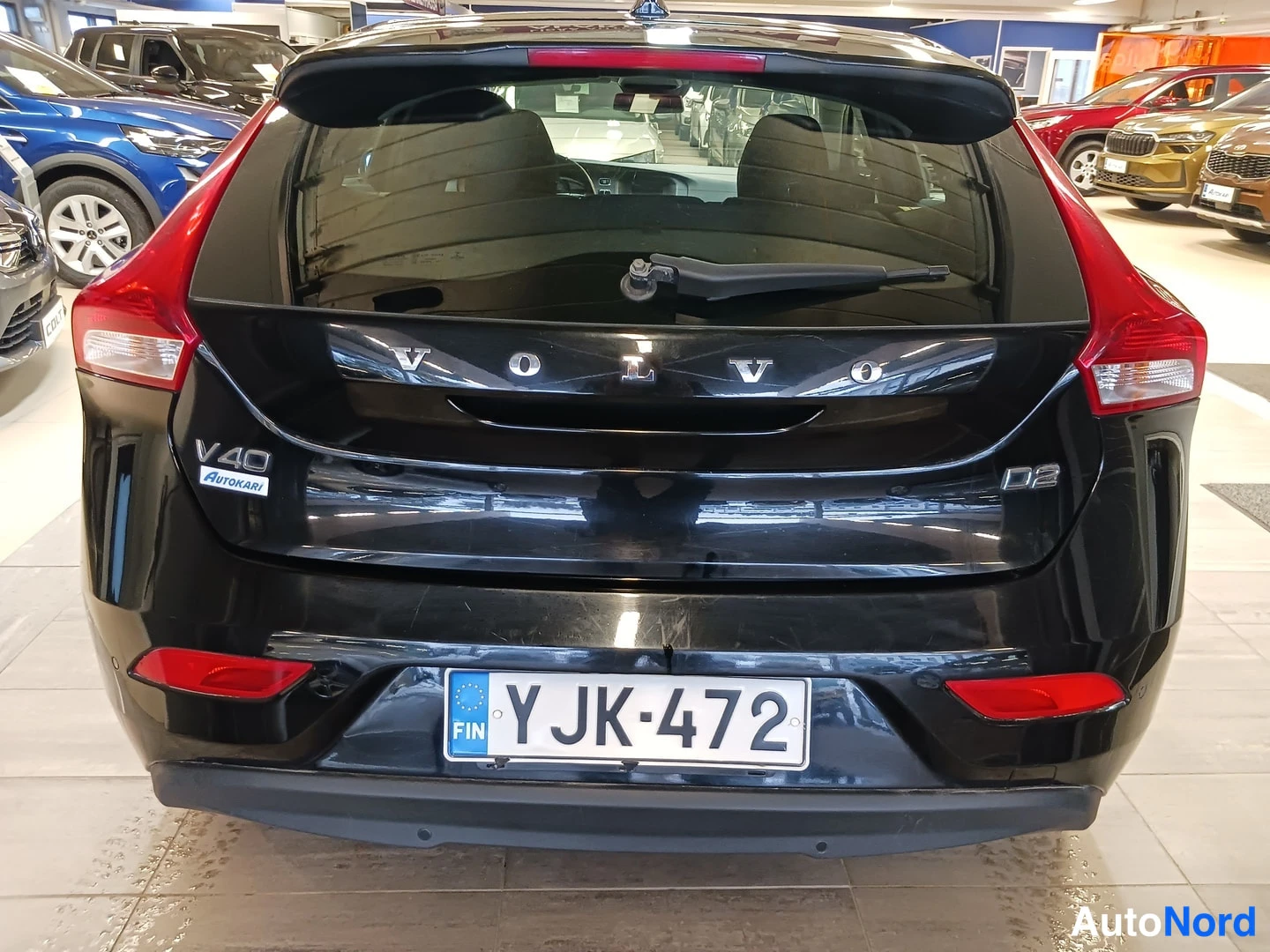 Takaa: Auton takaosa suoraan takaa: Volvo V40 D2 -merkinnät takaluukussa, rekisteritunnus ja punaiset takavalot.