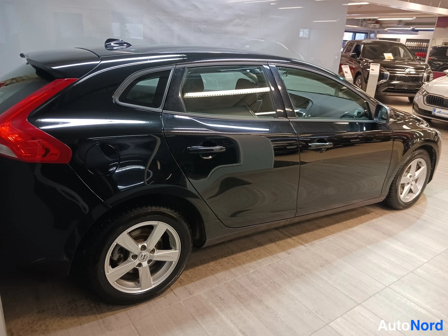 Takaviisto: Musta Volvo V40 takaa viistosti oikealta: takavalot, oikea sivu, viistetyt kevytmetallivanteet.