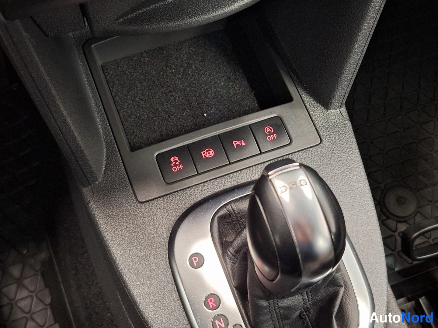 Yksityiskohta: Vaihteiston vieressä painiketaulu: ABS OFF, elektroninen käsijarru, parkettianturit (P), auto start/stop OFF; DSG-vaihteenvalitsimen kansi.