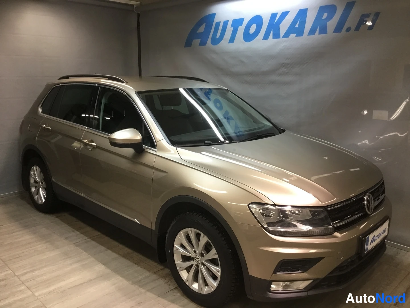 Etuviisto, nokka oikealle: Kultakeltainen Volkswagen Tiguan etviistöstä oikealta, katutalvirenoissa sisätiloissa