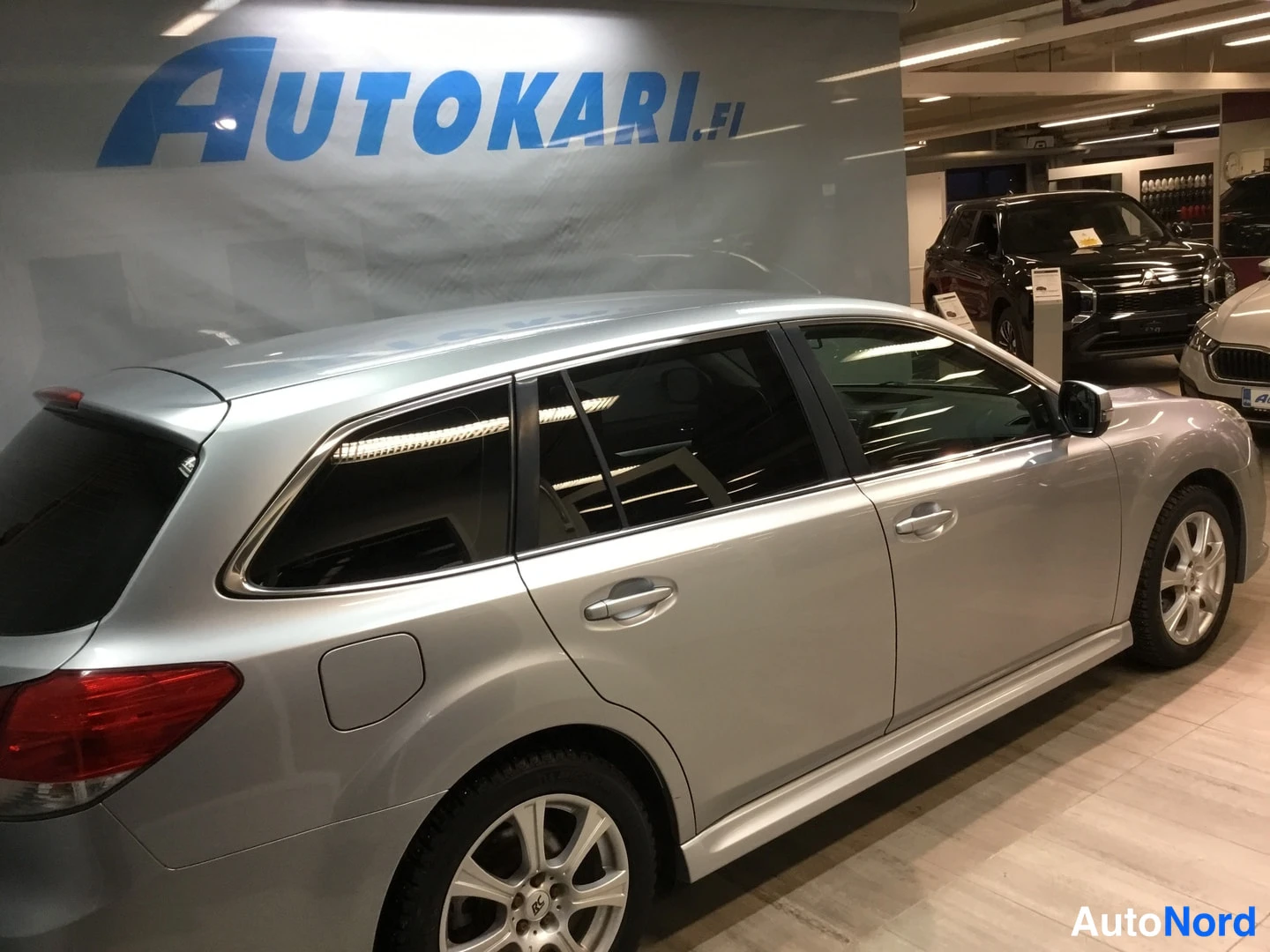 Takaviisto: Silver Subaru station wagon from the rear-left, full side profile visible including flanks, rear taillight and alloy wheels.