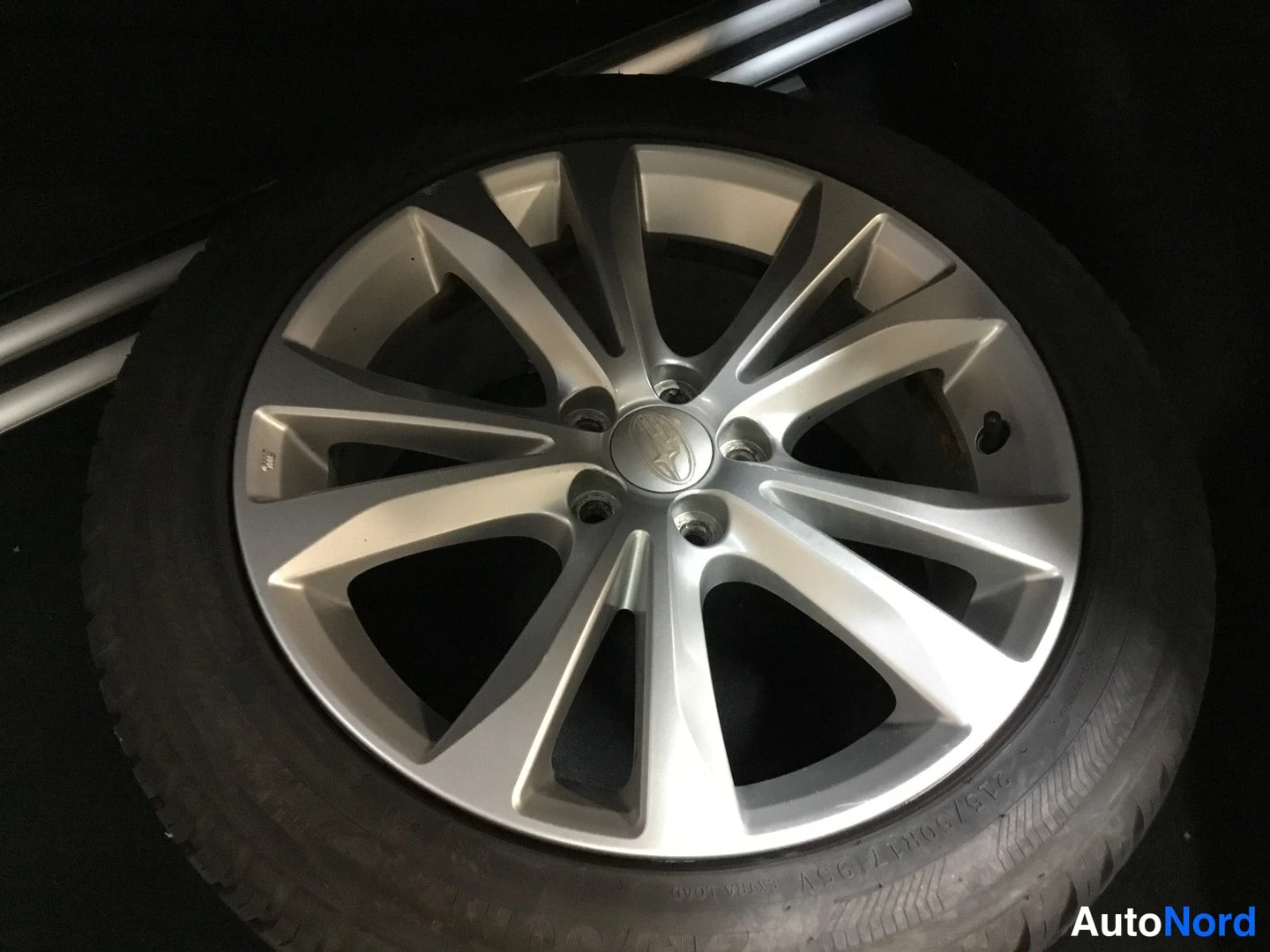 Muu: Lähikuva hopeaharmasta Subaru-kevytmetallivanteesta kumirenkaalla.