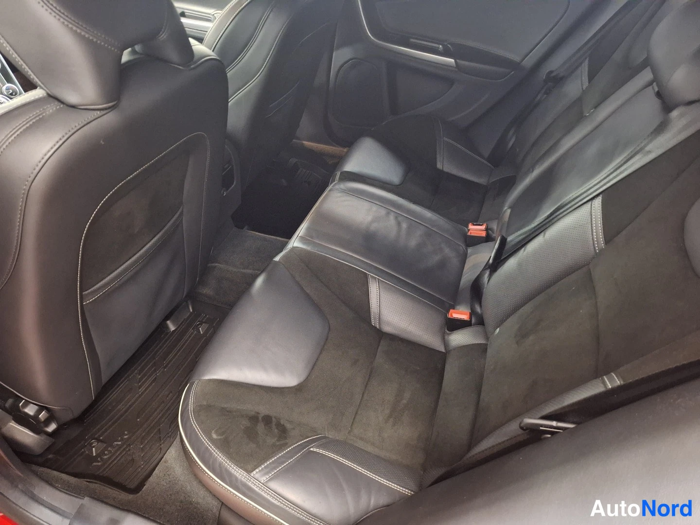 Muu: Takapenkki takaa katsottuna: musta nahka-suede-istuinrata ja Volvo-lattiamatto.