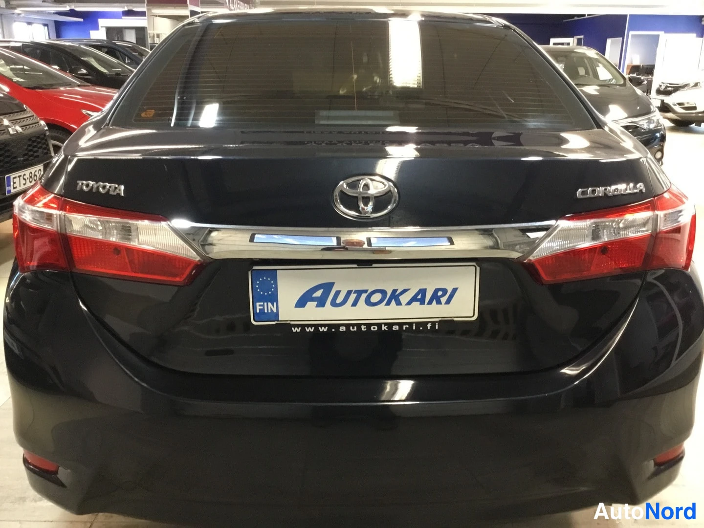 Takaa: Mustan Toyota Corollan takapää suoraan takaa, Toyota- ja Corolla-merkit takaluukussa, punaiset takavalot.