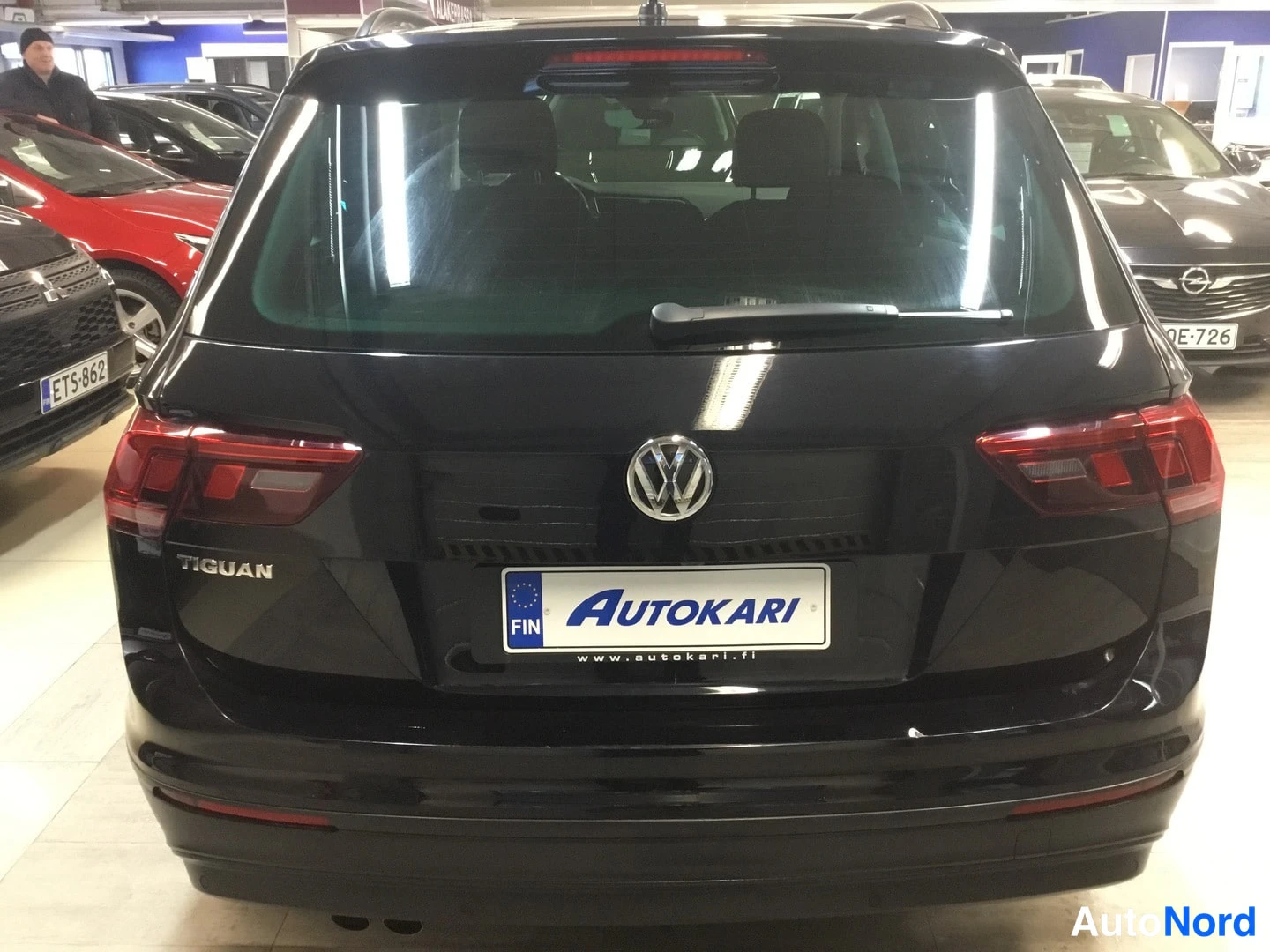 Takaa: Mustan Volkswagen Tiguanin takapää suoraan takaa, Tiguan-teksti ja VW-merkki takaovessa, Autokari-kilpi.