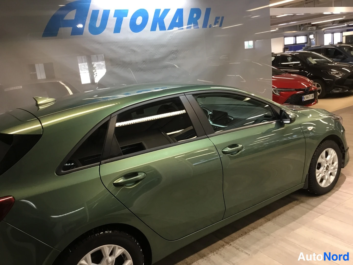 Takaviisto: Vihreä viistoperäinen henkilöauto sivulta takaa kuvattuna automaalissa, valkoiset vanteet.
