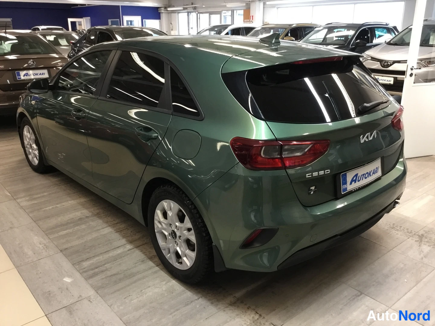 Takaviisto: Vihreän KIA Ceed -farmariauton takakulma näkyvissä sisätiloissa, rekisterikilpi Autokari.