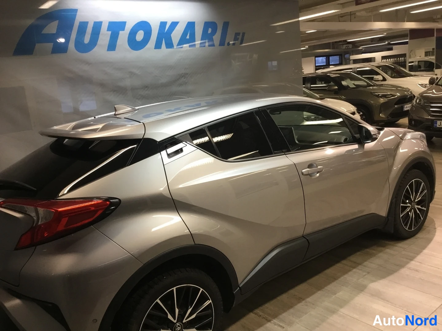 Takaviisto: Hopeanvärinen Toyota C-HR takaviistosta, takavalot ja korin sivut näkyvissä myymälätilassa.