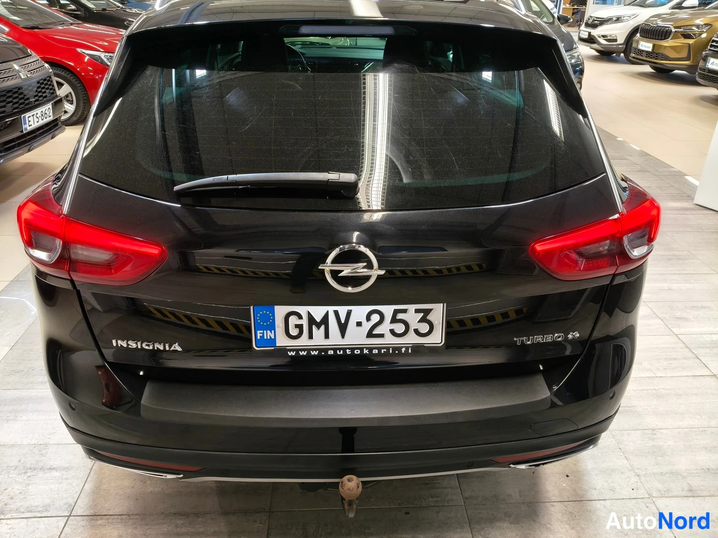 Takaa: Opel Insignia -farmarin musta takapää: takavalot, rekisterikilpi, merkki- ja mallitekstit sekä vetokoukku.