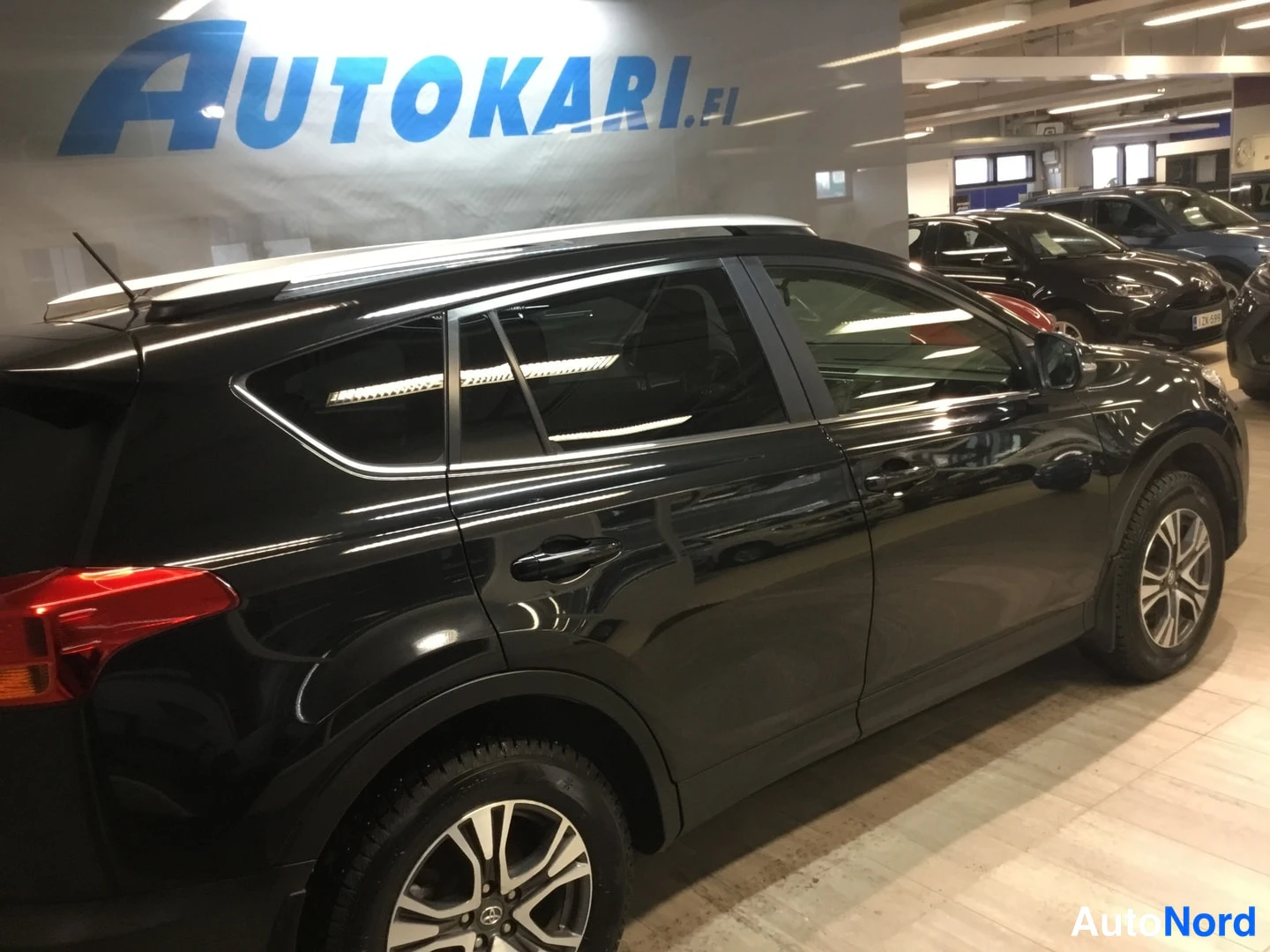 Sivulta: Mustan Toyota RAV4 -maasturin sivunäyttö oikealta puolelta sisätiloissa, katse suunnattuna taaksepäin.