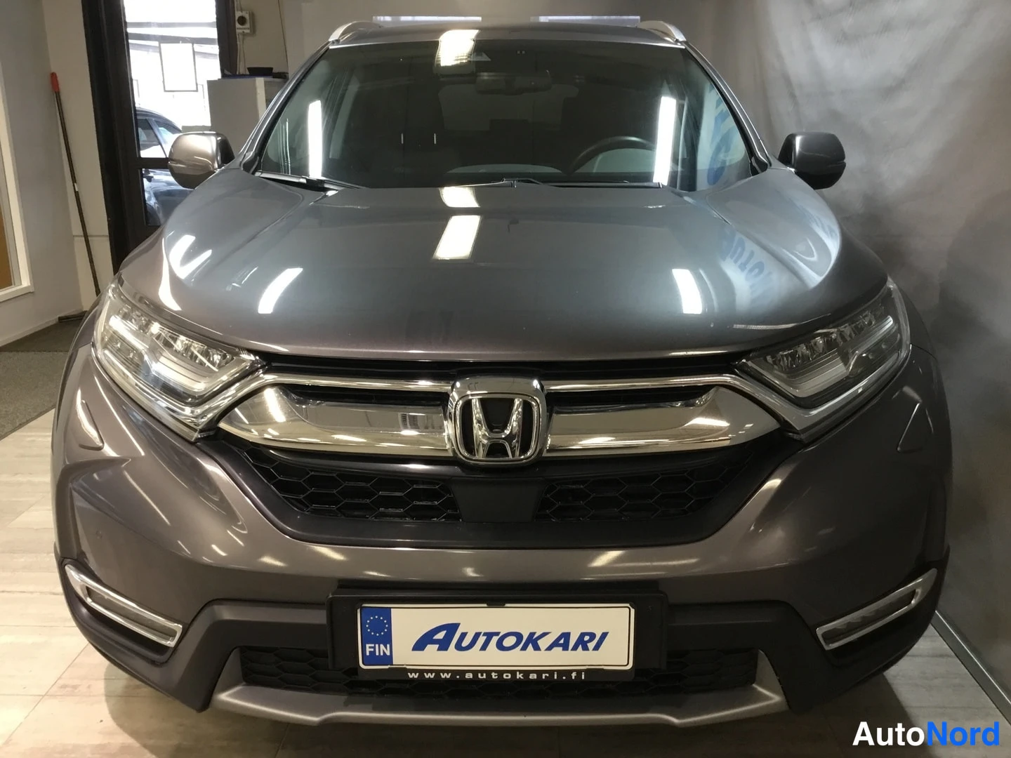 Edestä: Honda CR-Vin etunäkymä: kromikoristeinen etusäleikkö Honda-merkillä, LED-ajovalot ja Autokari-tunnus kilvessä.