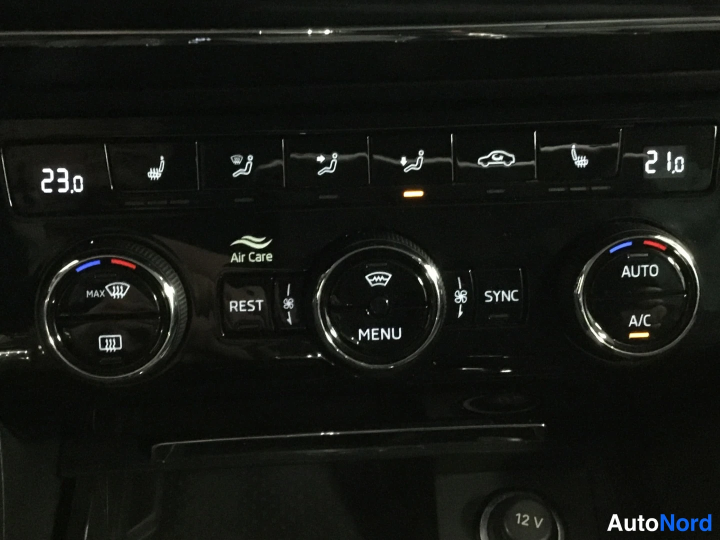 Muu: Auton ilmastointipaneeli: kaksipaikkainen säätö näytöillä 23.0 ja 21.0, napit REST, MENU, SYNC, AUTO, A/C sekä Air Care -merkintä ja 12 V -pistorasia.