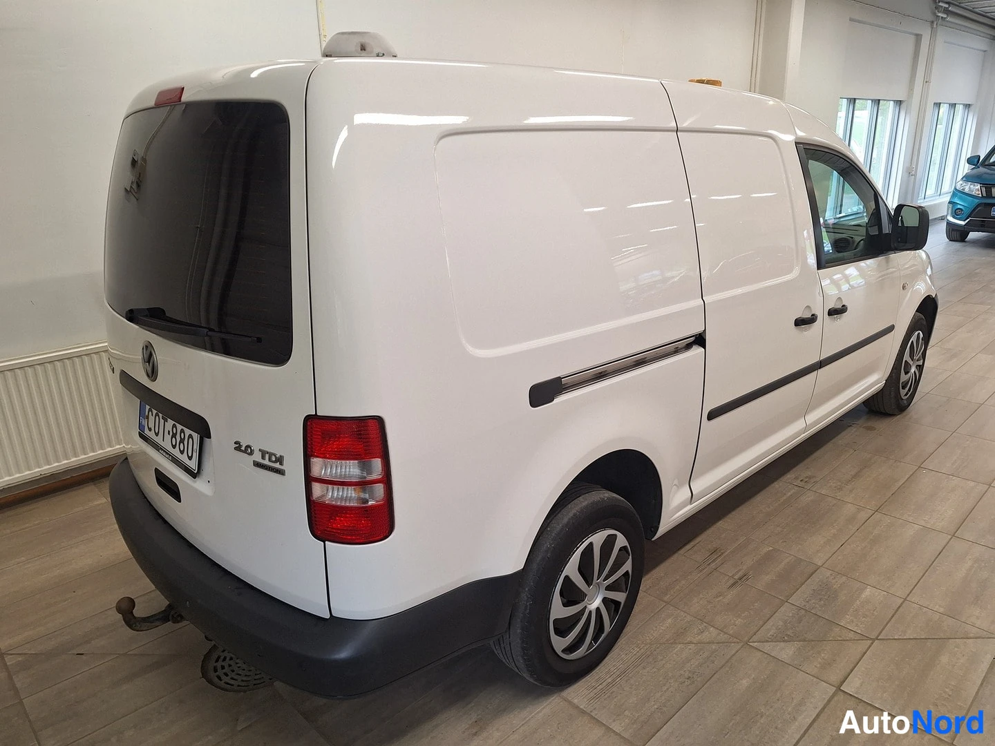 Sivulta: Valkoinen Volkswagen Caddy vasemmalta takaa