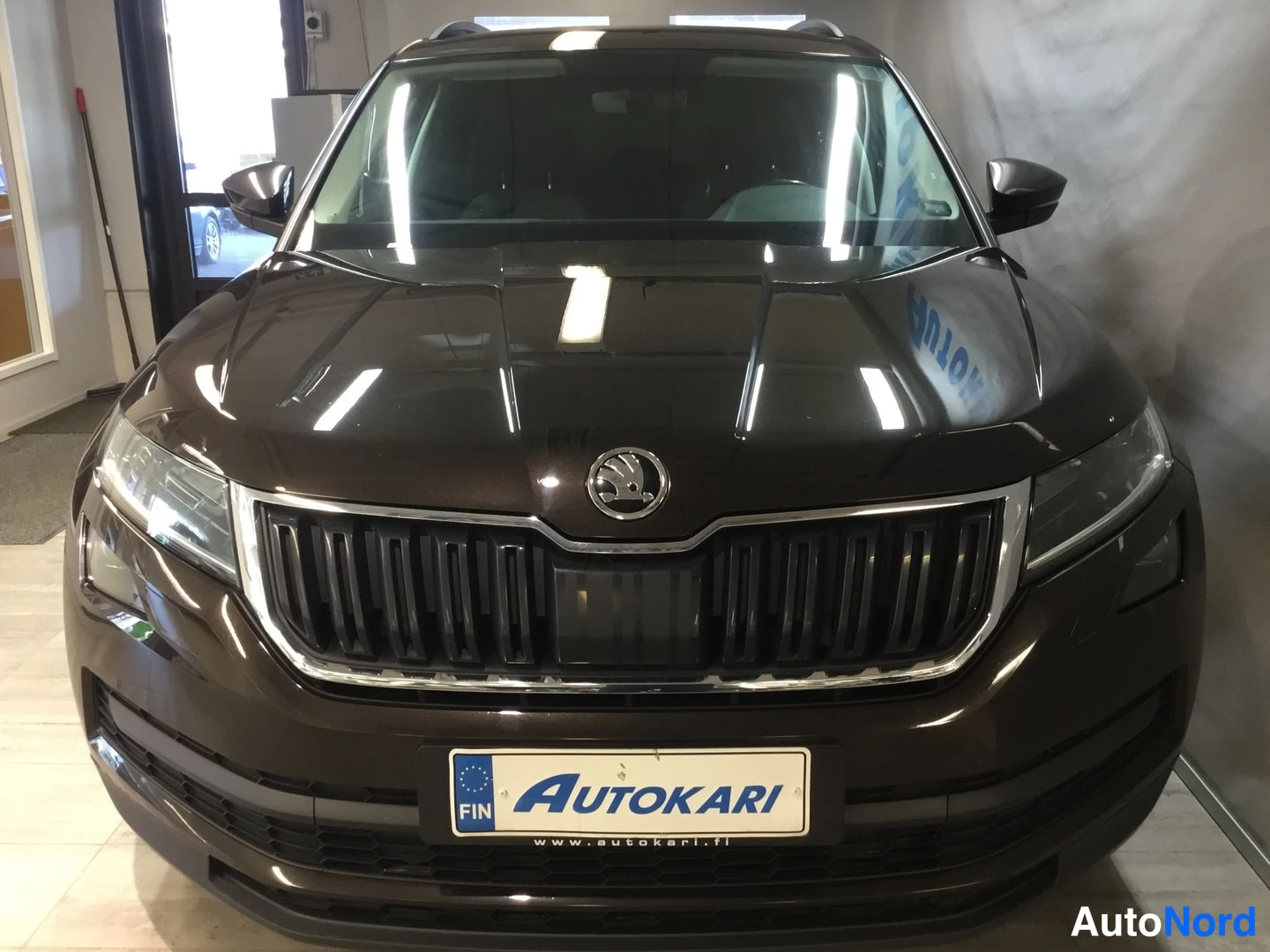 Edestä: Etukolmikulma-näkymä ruskeasta Skoda-kabista. Näkyvissä on eturitilä, Skoda-logon ja LED-edessäpysyvät.
