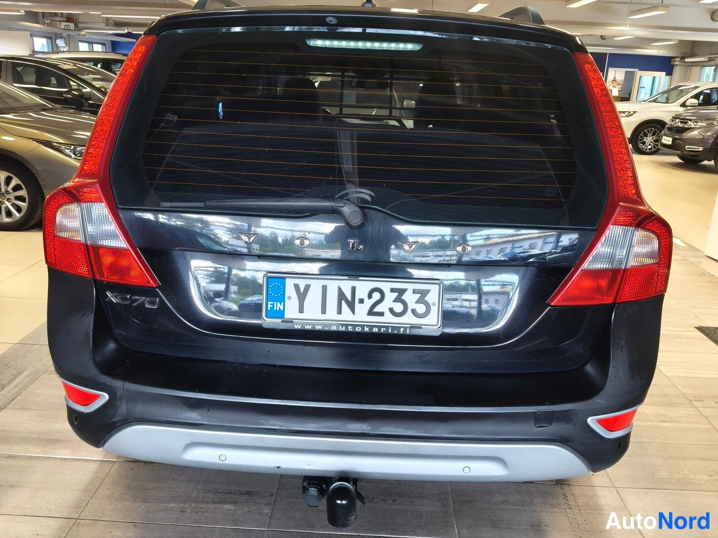 Takaa: Musta Volvo XC70 -seisauttaa sisätiloissa. Kuva on peräkuvaajassa jossa näkyy perävalot ja rekisterikilpi. Vetopyörä on näkyvissä.