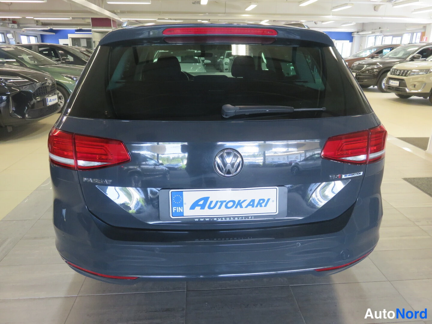 Takaa: Rear view of a Volkswagen Passat showing tail lights and VW badge. License plate holder displays 'AUTOKARI'.