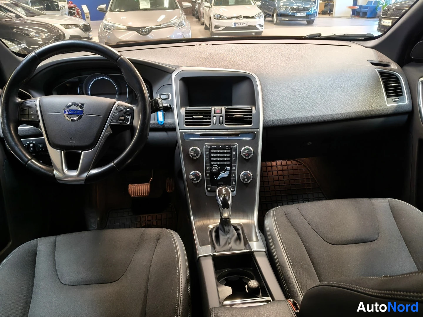 Muu: Autojen sisätila: Volvo-ohjauspyörä, kojelauta, vaihteenvalitsin ja kaksi etuistuinta.