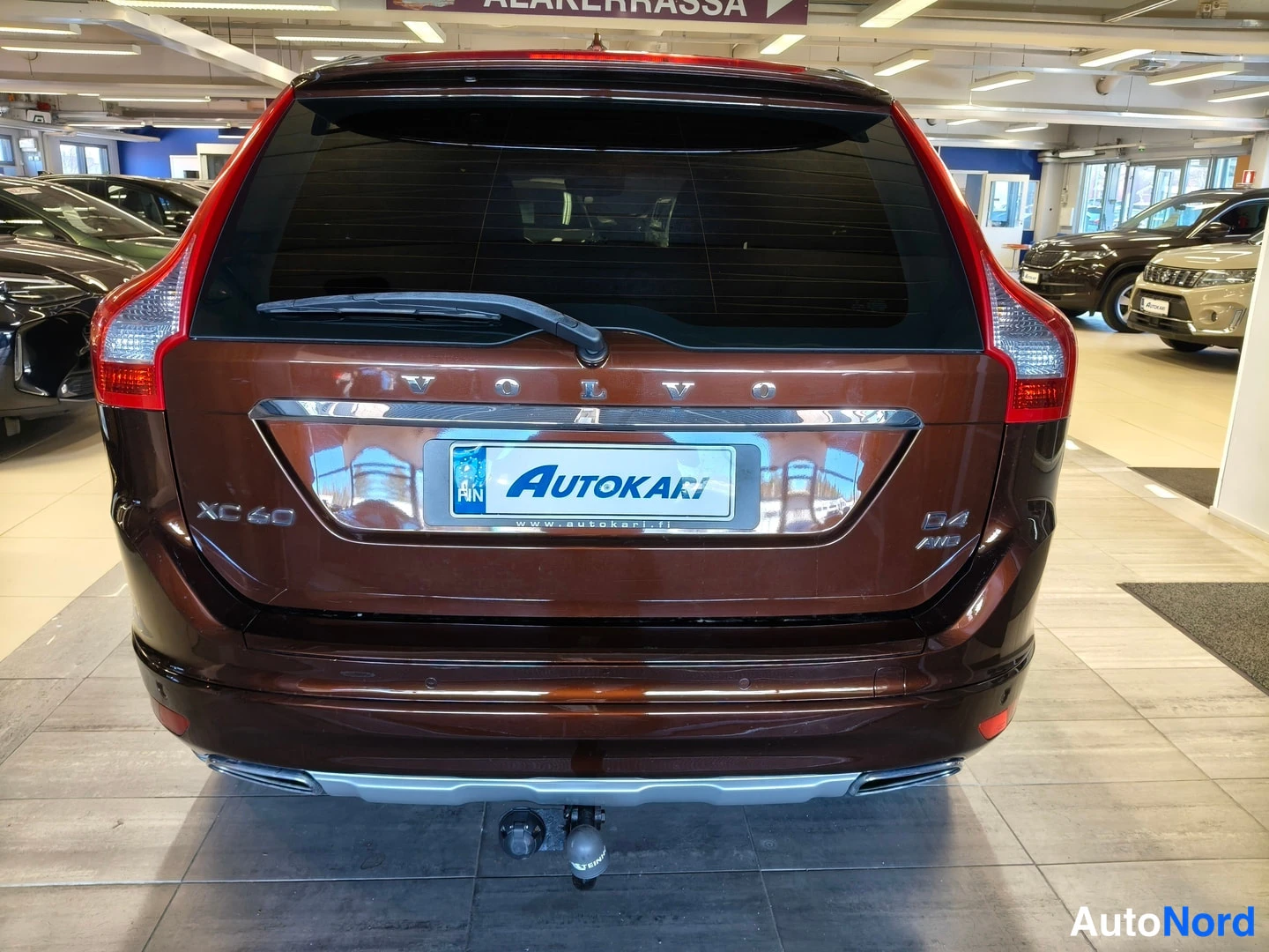 Takaa: Auton takanäkymä: ruskean roofan takapaneeli, VOLVO-teksti ja XC 60 -merkintä, Autokari-rekisterikilpi ja vetokoukku.