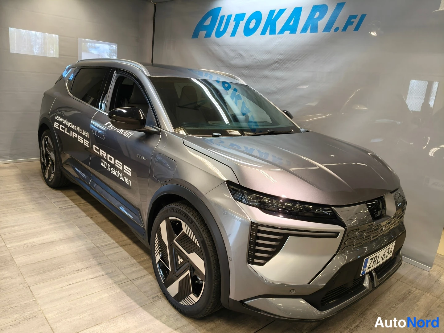 Etuviisto, nokka oikealle: Hopeanharmaa Mitsubishi Eclipse Cross etuviistosta oikealta, myyntitekstit ovissa ja rekisteritunnus näkyvissä.