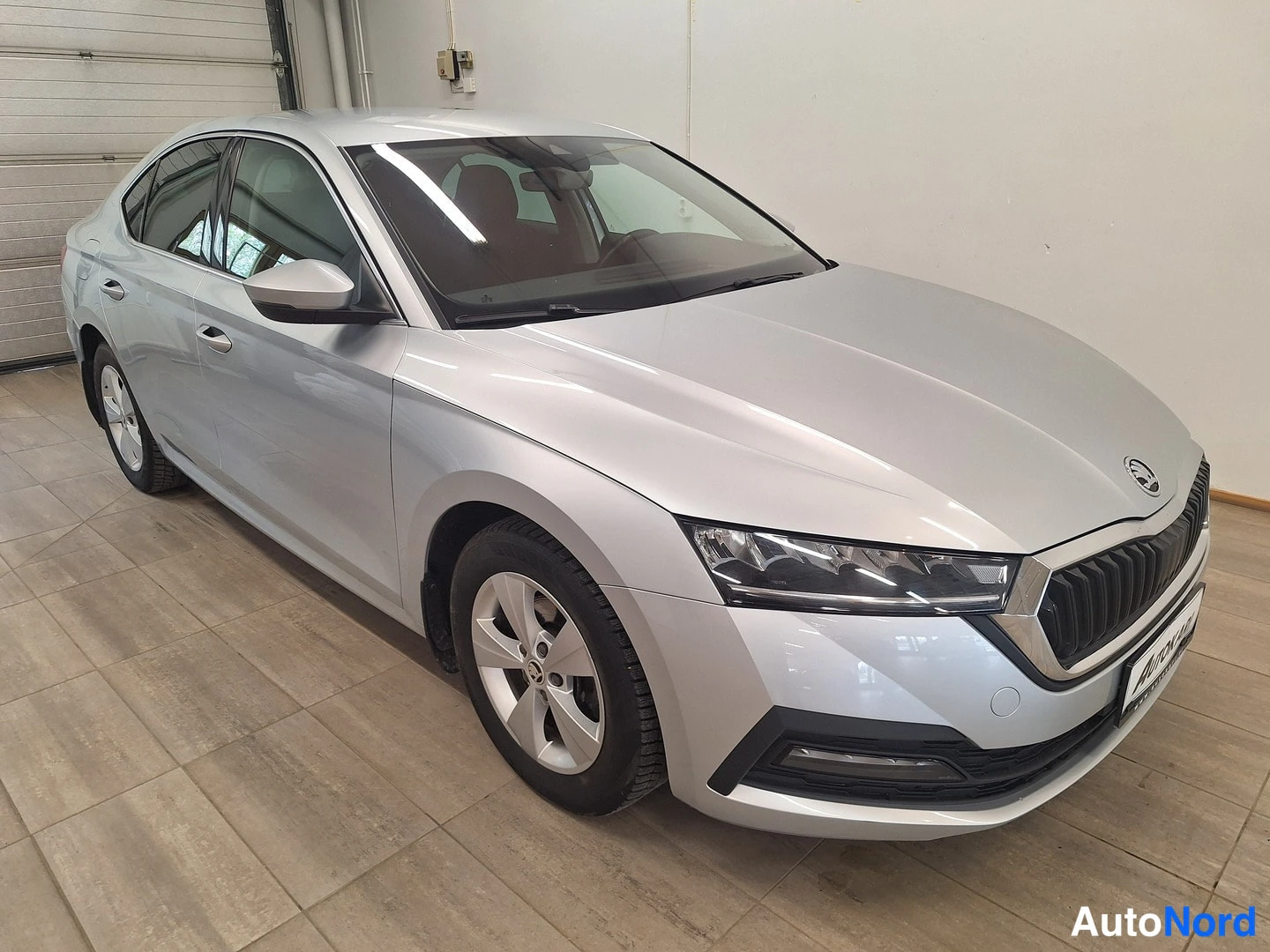 Edestä: Hopeanvärinen Skoda Octavia -sedan kuvattu kolmivartalokuva edestä vasemmalta sisätiloissa.