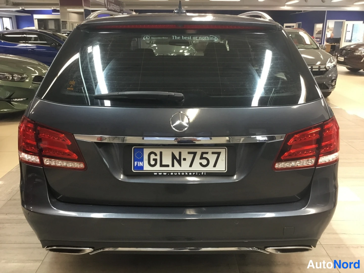 Takaa: Mercedes-Benz farmarin takapää suoraan takaa; punaiset takavalot, korotus ja tuplapakoputket näkyvissä.