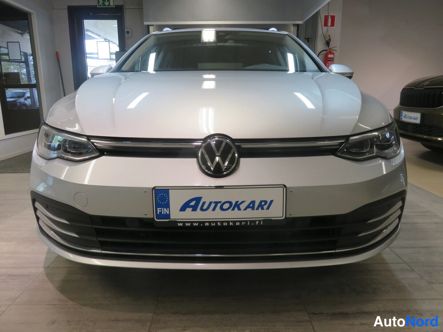 Edestä: Auton etupää suoraan edestä: Volkswagen-merkki, ajovalot ja AUTOKARI-tunnus kilvessä.