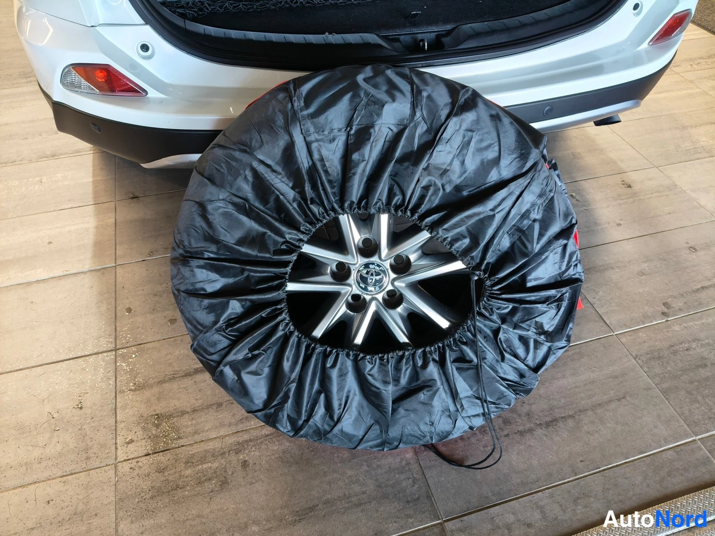 Takaa: Auton takaosa ja suojakassiin kieritetty varaovanne Toyota-kehdolla lattialla.