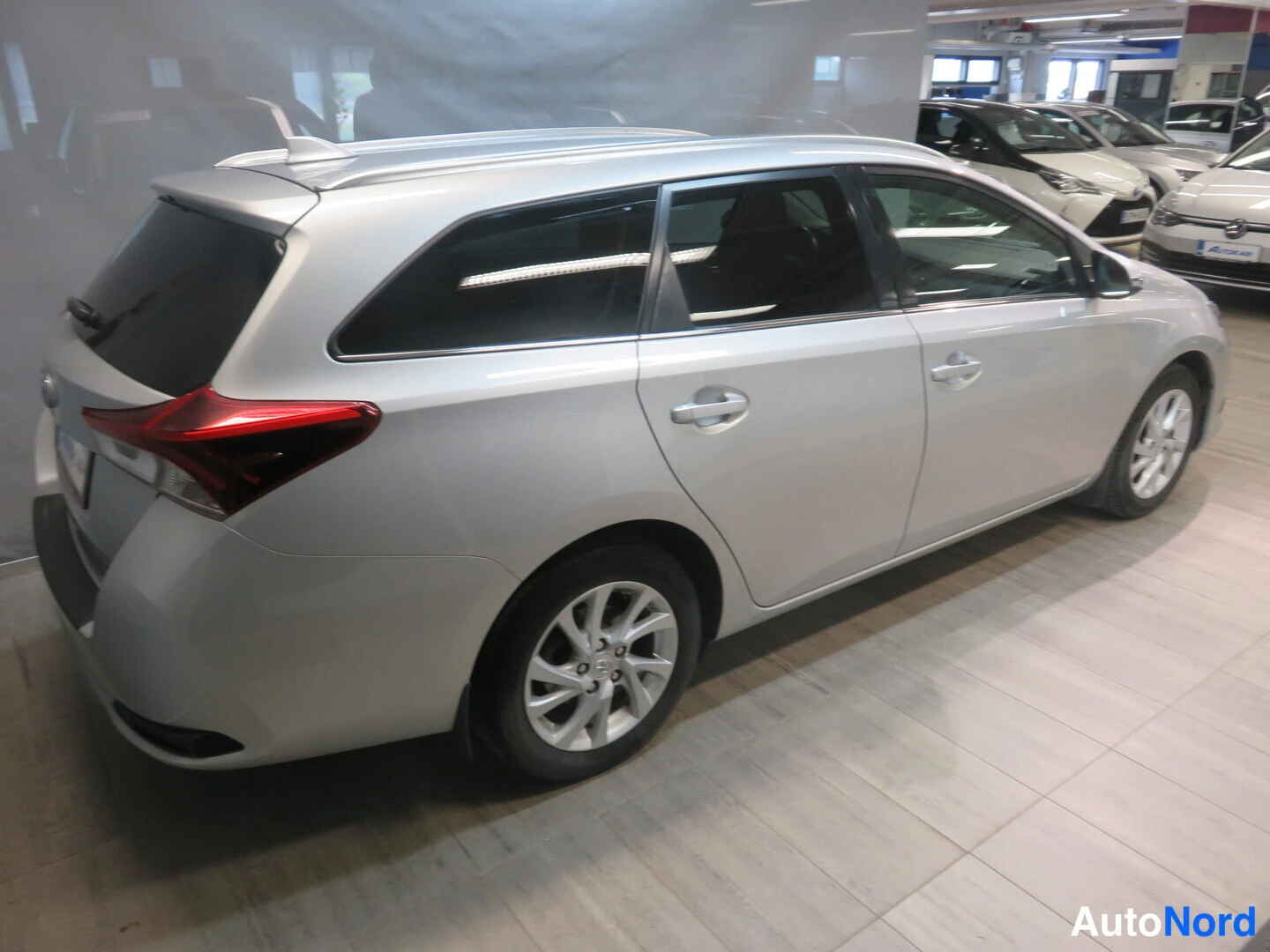 Takaviisto: Hopea Toyota Auris Touring Sports farmari takaviisto vasemmalta autosalon lattialla.