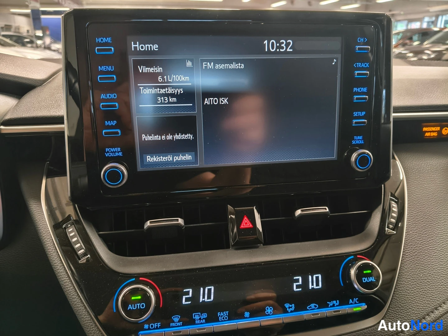 Muu: Auton infotainment-näyttö kotivalikossa kello 10:32, alapuolella kaksitoiminen automaattinen ilmastointipaneeli.