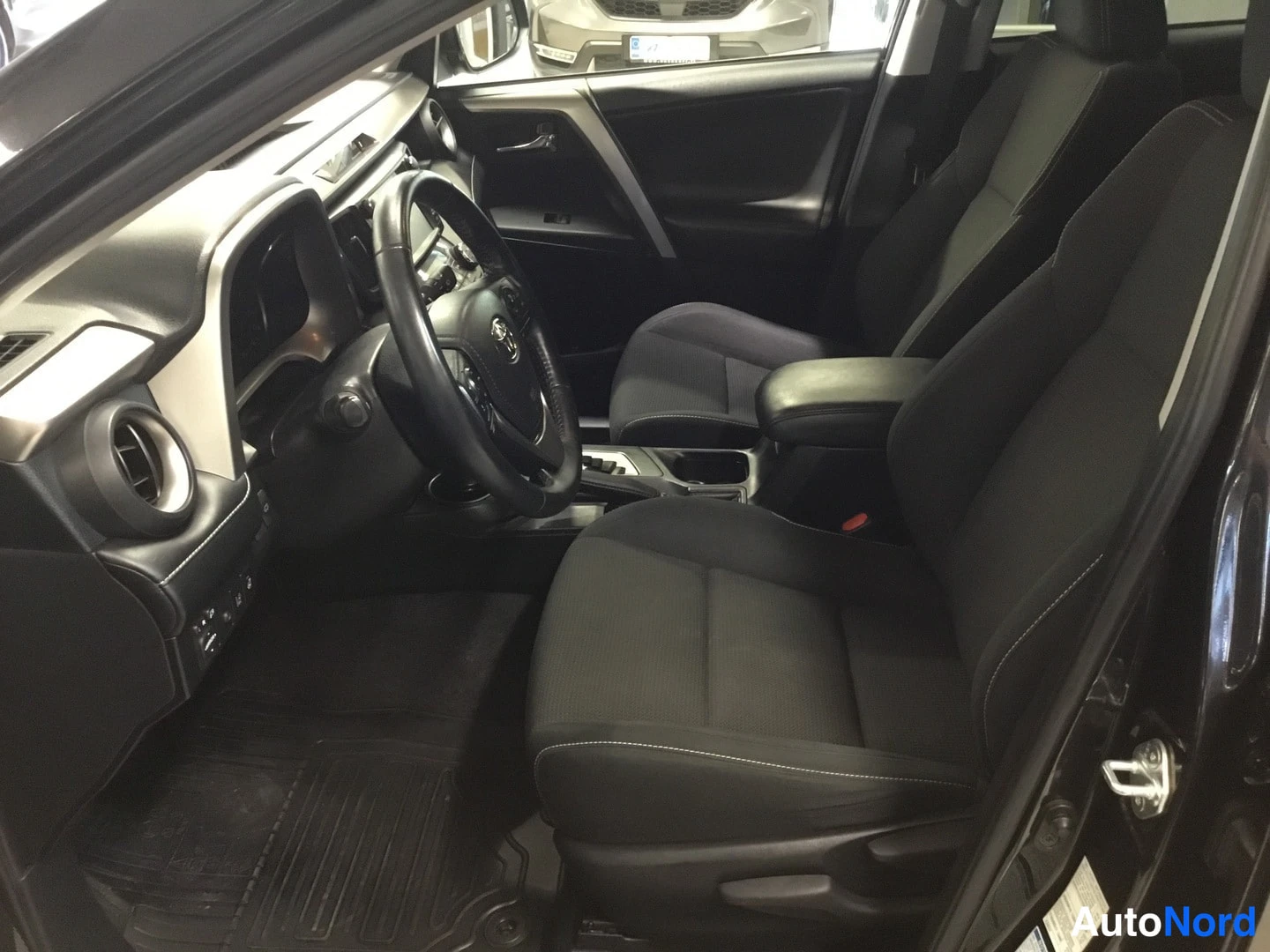Muu: Toyota RAV4:n etuistuimet ja ohjaamo kuljettajan oven auki ollessa, mustat kangasistuimet.
